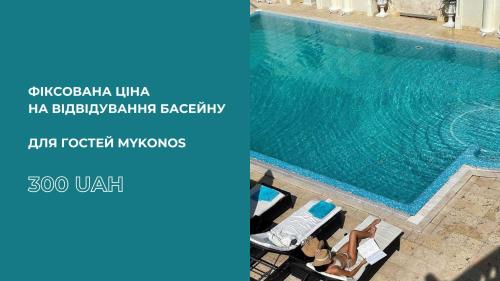 敖德萨Mykonos Hotel Apart Maestro的一座带椅子的大型游泳池,位于大楼旁