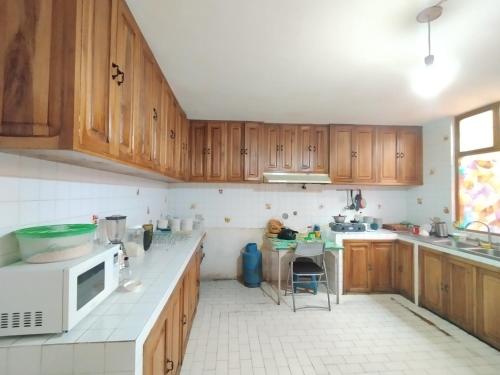 拉塔昆加Hotel Rosim Cotopaxi的厨房设有木制橱柜和白色瓷砖地板。