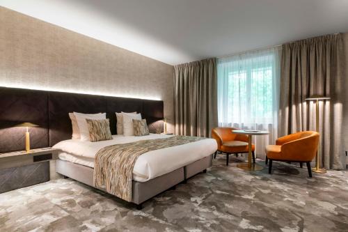 滑铁卢Van der Valk Waterloo的酒店客房带一张床、一张桌子和椅子