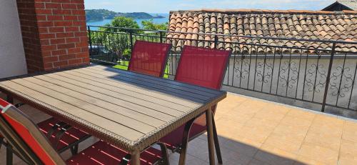 斯楚雅Sea view apartment Renzzo的阳台上配有一张木桌和两张红色椅子