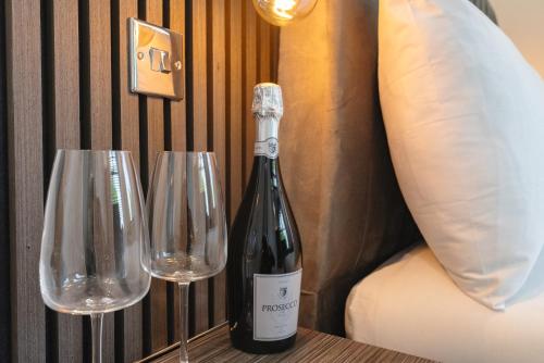 米德尔斯伯勒OYO Bellevue Apartments Middlesborough的桌子上放有一瓶葡萄酒和两杯酒