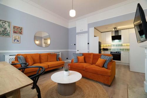 伦敦Lamington Apartments - Hammersmith的客厅配有2张橙色沙发和1张桌子