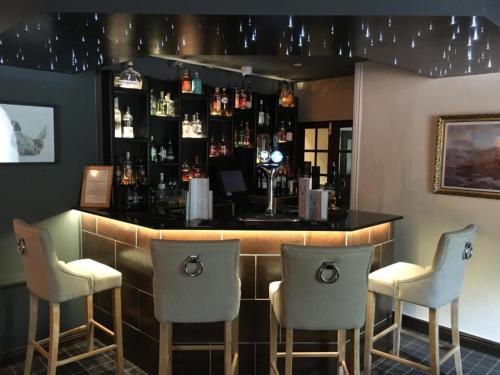 奥尔戈斯OYO Auldgirth Inn的酒吧配有三把椅子和带瓶子的吧台