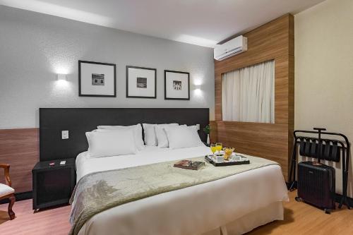 弗洛里亚诺波利斯坎比莱拉酒店的一间卧室配有一张大床,上面有托盘