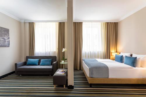 布达佩斯布达佩斯莱昂纳多酒店的配有一张床和一把椅子的酒店客房