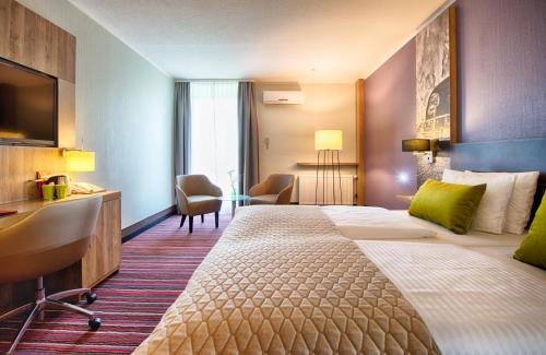 沃尔夫斯堡沃尔夫斯堡市中心莱昂纳多酒店的酒店客房设有一张大床和一张书桌。