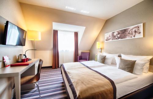 拉登堡曼海姆-拉登堡莱昂纳多酒店的酒店客房配有一张床、一张书桌和一台电视。