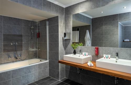 曼海姆莱昂纳多皇家曼海姆酒店的浴室配有两个盥洗盆和浴缸。