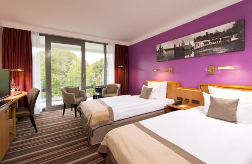 汉诺威汉诺威莱昂纳多酒店的紫色墙壁的酒店客房内的两张床