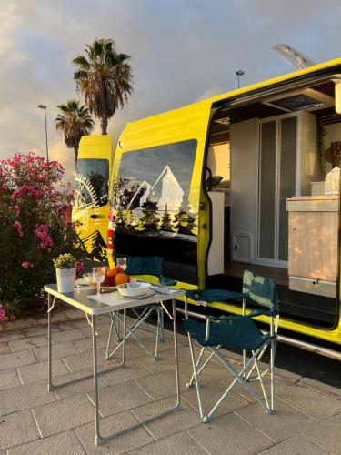 El GuinchoOn Road- feel freedom with campervan!的黄色面包车前面的桌椅