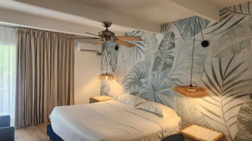 圣安德烈斯可可普拉姆海滩酒店的一间卧室配有一张带热带壁纸的床