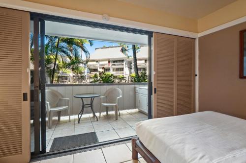 希洛Waiakea Villas 4-124的一间卧室配有一张床,阳台配有桌椅