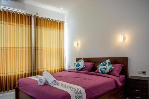 龙目岛库塔Turtle House Lombok的一间卧室配有两张紫色床单