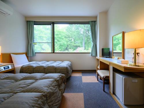 TagaRest Inn Taga的酒店客房配有两张床和一张书桌