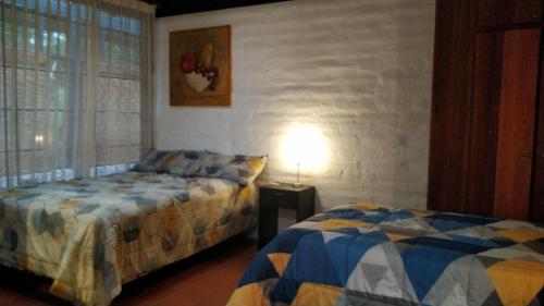 CumbayáCasa del Aguacate Cumbaya - Tumbaco的一间卧室设有两张床和一张桌子上的台灯。