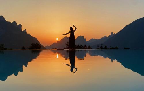 张家界XMAN Valley Sunrise Resort的日落时站在水面上的女人