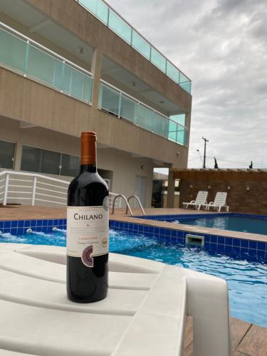 佩鲁伊比Pousada e Espaco AURORA Peruibe的游泳池畔的桌子上摆放着一瓶葡萄酒