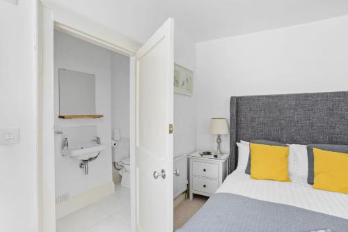 达特茅斯10 Clarence Hill - Elegant Town House with outside space的一间卧室配有一张带黄色枕头和水槽的床