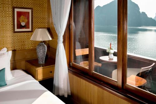 下龙湾下龙巴雅观光船的卧室设有窗户、一张床和一张桌子