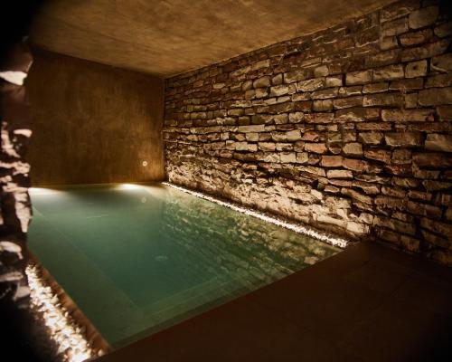 SaludecioLe Agavi Resort & SPA的石头墙房的游泳池,有砖墙格马克斯韦尔格马克斯韦尔