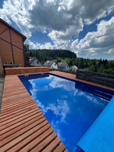 斯基希德尼萨Belvedere-Karpaty-Panorama的一个带木甲板和蓝色海水的游泳池