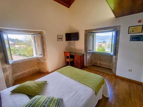 MiñortosCasa do Fieiro的一间卧室设有一张床和两个窗户。