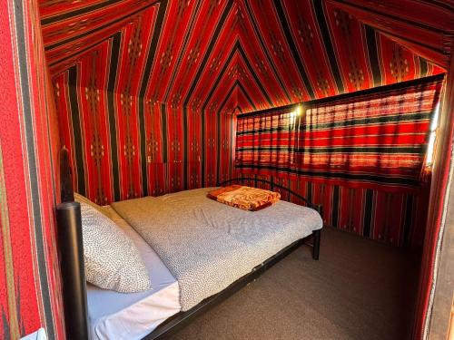 瓦迪拉姆Desert Bird Camp的一张小床,位于红色墙壁的房间