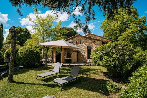 索维奇勒Borgo Il Poggiaccio Residenza d'Epoca的石头房子,配有两把椅子和一把伞
