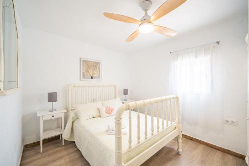 尼哈尔Cortijo El Pinar 1的卧室配有白色婴儿床和吊扇。