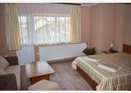 戈韦达尔齐Family Hotel Miglena的一间卧室配有一张床、一张沙发和一个窗口