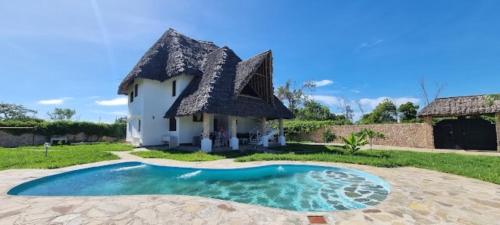 瓦塔穆Nyuso za Afrika的茅草屋顶和游泳池的房子