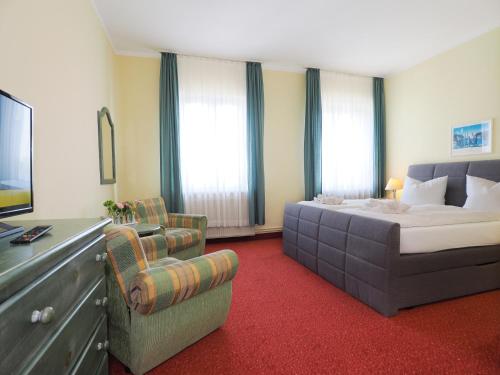 黑灵斯多夫Hotel See-Eck的一间卧室配有一张床、一张沙发和一把椅子