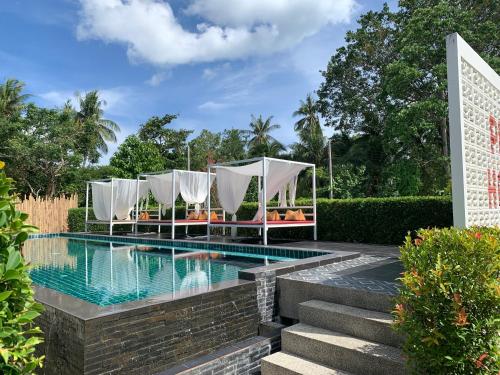 班泰Phangan Hometown Resort - Adults Only的一个带椅子的游泳池和一个毗邻度假酒店的凉亭