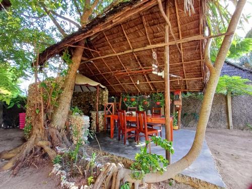 米查维Karibu Paradaizi的树下设有木桌和椅子的餐厅