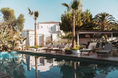 阿拉恰特ARTOTEL的一座房子旁的游泳池,游泳池旁设有椅子和棕榈树