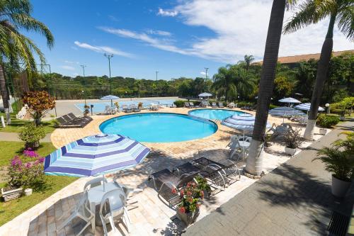 弗朗卡Hotel Dan Inn Franca & Convenções的一个带遮阳伞和椅子的游泳池