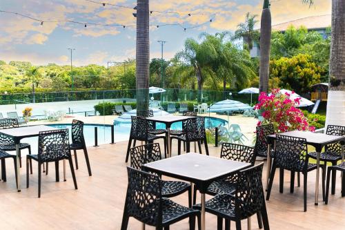 弗朗卡Hotel Dan Inn Franca & Convenções的游泳池旁带桌椅的天井