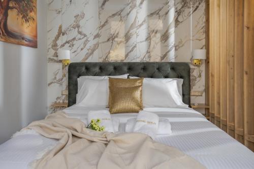 海若克利欧Royal Gold City Suites by Estia的一张配有白色床单和金色枕头的大床