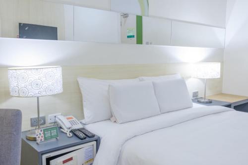 达沃市Go Hotels Lanang - Davao的一间卧室,配有一张床,在床头柜上配有电话