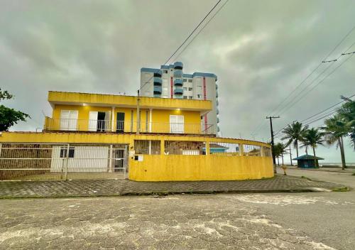 蒙加瓜Hostel Encanto de Mongaguá的一座高楼前的黄色建筑