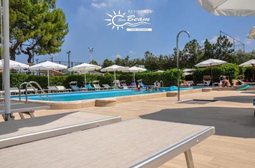 Leporano MarinaResidence Sunbeam的游泳池配有椅子和遮阳伞,周围的人可以坐在游泳池周围
