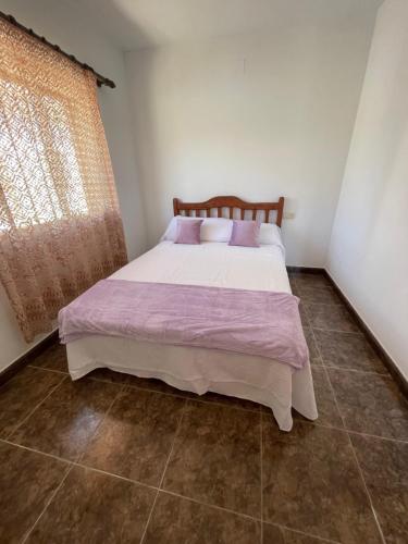 BenifalletLo Jardí de Benifallet的一间卧室配有一张带紫色床单的床和窗户。