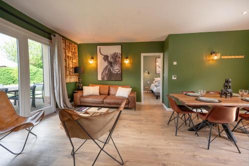 康村Hôtel Restaurant Le Fiacre à Quend plage的客厅设有绿色的墙壁和桌椅