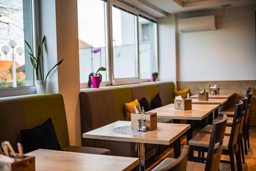施韦夏特阿里昂机场酒店的餐厅设有木桌、椅子和窗户。