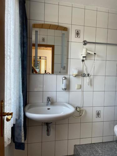 锡根舍费尔酒店的浴室设有白色水槽和镜子