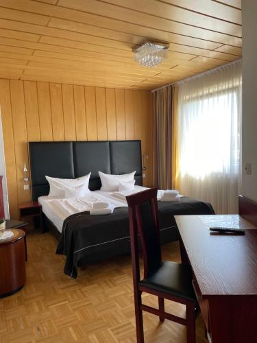 锡根舍费尔酒店的一间卧室配有两张床、一张桌子和一把椅子