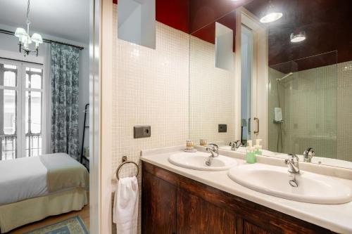 塞维利亚Komodo Sierpes: Bright & Classy Central Apartment的一间带两个盥洗盆和一张床的浴室