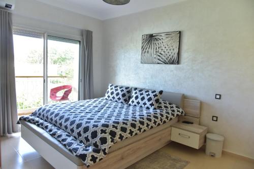 非斯Golf Royal appartement的一间卧室配有一张带蓝色和白色棉被的床