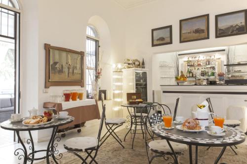 罗马皮兰德洛别墅酒店的客厅配有2张桌子和椅子以及壁炉