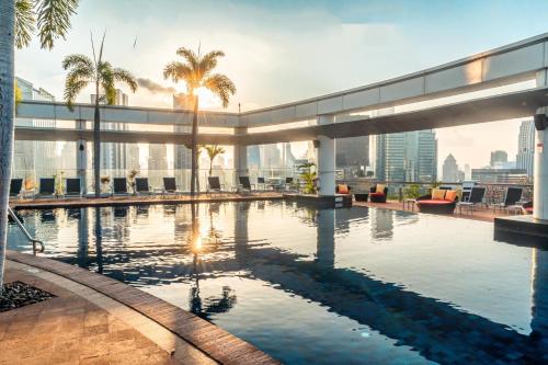 曼谷Centara Grand At CentralWorld的棕榈树建筑屋顶上的游泳池